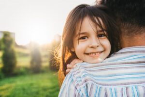 young smiling girl looking over shoulder of man holding her